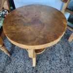 Mesa lateral redonda em madeira maciça, confeccionada a partir de seção sólida de tronco, evidenciando de forma natural os veios, anéis de crescimento e variações da madeira. Estrutura inferior com três pés curvos integrados a um prateleira circular, compondo desenho orgânico e escultural.A peça segue o conceito de mobiliário orgânico, valorizando a forma natural da madeira e sua textura, com acabamento acetinado que preserva a pátina e irregularidades originais. Dimensões: 0,63x0,62