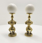 Par de castiçais em bronze dourado, com bases tripartidas de apoio e fustes esculpidos com painéis em relevo. As formas robustas e simétricas, associadas ao acabamento manual, evidenciam um trabalho artesanal de caráter decorativo asiático, possivelmente chinês, executado no início do século XX. Os bobeches circulares mantêm os pinos originais para fixação da vela. Dimensões: 25x5x5 centímetros.