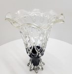 Imponente vaso decorativo em vidro artístico soprado, executado com a técnica de gotejamento estirado (droplet-pulled) formando uma estrutura reticulada em forma de trama entrelaçada, típica do trabalho manual de estúdio. A peça apresenta corpo vazado em vidro totalmente transparente, com aplicação de vidro negro no pé criando um contraste escultural marcante entre a leveza da parte superior e a base sólida, de linhas onduladas. dimensões:38x26 centímetros.