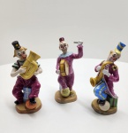 Conjunto de três figuras em porcelana Capo di monte, executadas à mão na Itália, cada uma representando um palhaço músico em trajes vibrantes. As peças exibem modelagem elaborada, pintura policromada típica da manufatura napolitana e expressão caricatural refinada. Cada figura traz marca Capo di Monte / Napoli sob a base. Dimensões:18x9 centímetros cada.