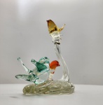 Escultura em vidro artístico Murano, pássaros multicoloridos. Delicada escultura em vidro artístico de Murano, representando três pássaros pousados em base orgânica translúcida. As figuras, modeladas manualmente, exibem elegantes nuances em tons de âmbar, verde-água e vermelho alaranjado, com perfeita transparência e movimento fluido característico do vidro soprado veneziano. Altura: 20 x 18 x 13 centímetros.