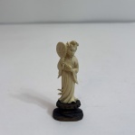 Pequena escultura representando figura feminina oriental trajando vestes tradicionais e segurando leque, ricamente esculpida em marfim natural, com delicados detalhes no rosto, cabelos e drapeado das vestes. medindo: