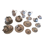 Guarnição para chá e café em porcelana Steatita decorado com singelas flores e dourado sobre fundo branco composto de: 2 bules, 1 cremeira, 1 manteigueira, 1 açucareiro, 1 prato para bolo, 12 xícaras para chá com pires, 12 xícaras para café e 12 pratos para bolo: 42 peças.