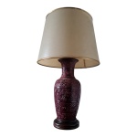 Vaso em porcelana oriental lavrado em alto relevo na cor vinho adaptado para luminária de uma lâmpada com cúpula de pergaminho e apoiado em peanha de madeira, Alt. 81, Diam. 38 cm.