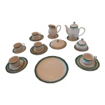 Guarnição para chá  em porcelana Vitramik Oxford, em porcelana creme levemente frisada com bordas verdes composto de:  5 xícaras para chá,  1 bule, 1 cremeira, 1 açucareiro e manteigueira, Diam. 19 cm. 4 pratos para sobremesa e 1 prato para bolo,  (cremeira e bule com imperceptíveis bicados),  Alt. 20 a 10,Total: 14 peças.