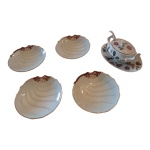 Cinco peças em porcelana sendo quatro travessas com bordas onduladas e fios dourados e pequena molheira com presentoir e concha pintada à mão, Diam. 12  e 10 x 15, Alt. 7 cm.