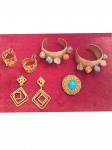 Cinco bijuterias em metal dourado: dois braceletes adornados com peras brasileiras, 1 broche cravejado de pedras azuis e 2 pares de brincos.