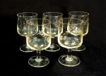 VIDRO, cinco (5) taças de pé alto para vinho, furta cor amarela, translúcidas, bojo com singela lapidação vegetalista, fuste quase cilíndrico, base em bolacha, medindo 13 cm altura e 7 cm diâmetro, uma com bicado na borda, sinais de uso, vide foto.