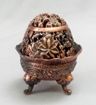 BRONZE, um (1) incensório de formato ovoide, tampa vazada e relevada em elementos vegetalistas, pés terminando em cabeças de elefante, base com barrado grego e elementos vegetalistas, assinada em caracteres orientais, confeccionado em metal cobreado, medindo 9 cm altura, peso aproximado 243 gr., vide foto.