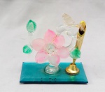 ESCULTURA, uma (1) representando beija flor, confeccionada em vidro na técnica dos Grandes Mestres Vidreiros de Murano, base espelhada, traz em um dos lados haste para caneta em metal dourado, medindo 10 x 6 x 9 cm, sinais de uso, vide foto.