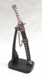 CUTELARIA, uma (1) miniatura de Katana, confeccionada em materiais variados, medindo 16,5 cm comprimento, acompanha suporte expositor, vide foto.