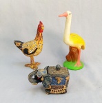 ESCULTURAS, três (3) animalistas distintas: 1 representando galinha, entalhada em madeira e policromada, medindo 17,5 cm altura; 1 representando garça, confeccionada em cerâmica branca, policromada, medindo 22 cm altura; 1 representando elefante (caixa com tampa), confeccionada em resina policromada, apliques em purpurina, medindo 12 cm comprimento, vide foto.