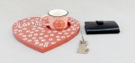 DIVERSOS, três (3) itens: 1 chaveiro em aço, representando gato, medindo 8 cm; 1 porta cartões confeccionado em PU e alumínio, medindo 9,5 x 6,5 x 1,5 cm; 1 xícara em porcelana com pires no formato de coração em MDF (Medium Density Fiberboard ou chapa de fibra em madeira de média densidade), ornamentação pintada em tons de rosa e branco, motivos de café, medindo a maior peça 20 x 20 cm, pouco uso, vide foto.