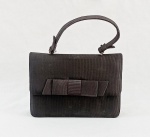 ACESSÓRIO FEMININO, uma (1) bolsa de festa, confeccionada em tecido gorgorão na tonalidade preta, alça de mão, detalhe com laço, fechamento por pressão, forrada, medindo 19 x 13 x 6 cm, usada, pequena mancha, vide foto.