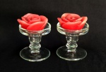 VIDRO FRANCÊS, par (2) castiçais, incolores e translúcidos, fuste no formato de balaustre, base em bolacha, legenda de origem FRANCE em relevo na própria modelagem, acompanham duas velas no formato de flor na tonalidade vermelha, medindo 8 cm altura e diâmetro, vide foto.