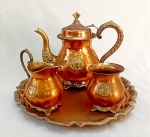 COBRE E BRONZE, baixela Indiana para chá com quatro (4) itens: 1 bule; 1 cremeira; 1 açucareiro e 1 bandeja, confecção artesanal com detalhes relevados em elementos vegetalistas, destaque para moldura circular representando KANGAYAN (raça zebuína de origem indiana), pode ser confundido erroneamente com MARKHOR (espécie de cabra que habita da Índia ao Paquistão), medindo a maior peça 30,5 cm diâmetro, sinais de uso, vide foto.