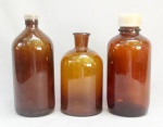 VIDRO, três (3) antigos frascos de farmácia, distintos, tonalidade âmbar, translúcidos, medindo o maior 23 cm altura, sinais de uso, vide foto.