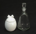 VIDRO E FAIANÇA, dois (2) itens distintos: 1 garrafa de whisky escocês vazia, incolor e translúcida, medindo 25,5 cm altura; 1 pote com tampa, formato ovoide, tonalidade branca, pega da tampa modelada na forma de laçarote, manufatura LUIZ SALVADOR (destacado mestre da arte de pintura em faiança na olaria de Alcobaça em Portugal, veio para o Brasil e fundou no ano de 1950 uma fábrica em Itaipava, região serrana do Rio de Janeiro, ainda em atividade), medindo 14,5 cm altura, começando a craquejar, característica do envelhecimento de toda a faiança, bicado na borda da tampa, ambos com sinais de uso, vide foto.