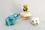 ESCULTURAS, três (3) distintas: 1 representando elefante, confeccionada em porcelana, tonalidade azul turquesa, medindo 8,5 cm comprimento; 1 representando porquinho, confeccionado em porcelana policromada, medindo 4,5 cm altura; 1 souvenir de búzios, confeccionada com conchas e outros materiais, faltando partes, medindo 11 cm altura, vide foto.
