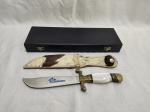 Antiga faca, punhal em inox com pega em madrepérola e cabeça de leão em bronze, bainha em pelo de vaca, na caixa original. Medindo 27,5cm de comprimento total. Monogramado Manoel gomes Moreira.