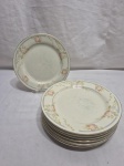 Jogo de 7 pratos de sobremesa em porcelana floral. Medindo 19cm de diâmetro. Com desgaste na douração.