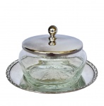 Açucareiro em metal espessurado à prata, presentoir com borda em relevo cinzelado, tampa com puxador esférico, recipiente em vidro translúcido, incolor e fundo estrelado. Med. 7cm de altura  e 13,5cm de diâmetro.
