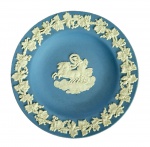 WEDGWOOD - Pequeno Prato em porcelana de biscuit na cor azul claro com detalhes em alto relevo com ramos de parreira na borda e figuras mitológicas no centro. Med. 11cm de diâmetro.
