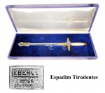Colecionismo/militaria/Brasil - (JL-08) Espadim da Policia Militar (Rio de Janeiro e outros estados), denominado `Tiradentes`. Peça de manufatura anos 60/70 da Metalúrgica Abramo Eberle, de Caxias do Sul-RS. Peça em estojo de luxo, muito provavelmente, material de presenteação, pois há vestígios, na caixa, de que havia uma placa com dedicatória. Peça muito rara de se ver dotada de caixa de presenteação original. O espadim está em excelente estado de conservação, aparentando nunca ter sido usado, a caixa original, além das marcas de uma provável placa de presenteação, aparenta ter sido exposta em vitrine, recebendo os raios do sol, isso pode ser visto pelo acentuado desbotamento do tecido original, Mas, o tecido internamente está íntegro, apresentando uma bela tonalidade azul. A caixa está sólida e plenamente operacional, apenas o tecido se encontra desbotado. Material vendido no estado em que se encontra e de acordo com as fotos do anúncio.