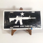 MILITARIA - PLACA DE AUTOMÓVEL - COME AND TAKE IT, com a imagem de um fuzil AR-15. Sem uso, parcialmente embalada com plástico. Mede aprox. 30,5 x 15 cm. Feita em alumínio. Come and take it é uma expressão histórica de desafio, originada na Antiguidade com o Rei Leônidas de Esparta na Batalha das Termópilas e utilizada mais tarde na Revolução Americana e na Revolução do Texas, na qual a famosa bandeira Come and Take It se tornou um símbolo de resistência e independência, particularmente no Texas.