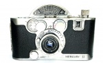 Colecionismo/maquinas fotográficas- (JL-19) Rara câmera Mercury II (made in USA), produzida a partir do fim da Guerra, em 1945, com a marca visual característica do semicírculo na parte superior, solução adotada para acomodar o curioso obturador circular e giratório. Trata-se de uma Mercury I (lançada em 1938) que adotou o filme 35 mm comum, ela era uma câmera de meio quadro, ou seja, dobrava a quantidade de exposições de um filme 35 mm, como foi o caso da posterior Olympus Pen (fazia 72 exposições em um filme de 36 quadros). Uma máquina não muito comum no Brasil, ainda mais em bom estado. O exemplar em leilão está em muito bom estado de conservação e funcionamento. Câmera vendida no estado em que se encontra e de acordo com as fotos. Poderá ser fornecido um vídeo mostrando o funcionamento da câmera.