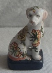 Escultura representando cachorro toy oriental em Porcelana craqueada, fundo braco decorado com florais, base em porcelana preta. Med. 16cm alt x 9cm comprimento x 6,5 cm de largura.