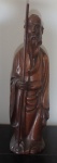 Escultura em madeira nobre entalhada - Sábio Oriental com bastão, medindo 38 cm de altura.