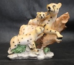 Grupo de onça em resina policromada, felino e suas duas crias sobre tronco de árvore. Med.18 x 20cm.