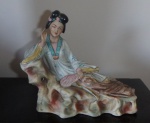 Escultura em porcelana policromada oriental  representando gueixa sentada relaxando, detalhes em douração, É uma peça para colecionadores, destacando-se pela riqueza de detalhes e qualidade artesanal. med. 18 x 20,5cm;