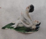 Estatueta de porcelana de casal oriental em cenas eróticas  sobre folha, representando a fertilidade. Med.7,5cm x 4cm