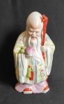 ARTE ORIENTAL - ECULTURA DE PORCELANA -  Sábio da Longevidade, Shou Xing (ou Shou Lao Xing), que é uma divindade popular chinesa. A figura é frequentemente retratada com uma cabeça calva proeminente e uma longa barba branca. Os atributos comuns associados a ele, como vistos na imagem, são um cajado e um pêssego, ambos símbolos de longevidade  - Alt. 23cm