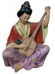 Escultura japonesa em porcelana fina, representando uma figura feminina musicista tocando um instrumento de cordas semelhante a um banjo ou pipa. numerado na base com o número 3. Medidas 22,5cm x 14cm x 10cm