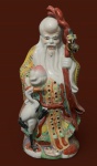 Escultura chinesa em porcelana do sábio  Shou Lao, o deus da longevidade na mitologia chinesa. A figura representa um imortal taoísta, tradicionalmente associado à saúde e vida longa. É frequentemente retratado com uma expressão sorridente, barba longa e branca e uma cabeça alongada. Normalmente, segura um pêssego (símbolo de vida longa) e um cajado. A garça, às vezes presente, também é um símbolo de longevidade na cultura chinesa.  - Altura 43 cm