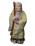 Estatueta de porcelana chinesa representa Shou Xing, o deus da longevidade. É uma das três estrelas da fortuna na mitologia chinesa. A figura é frequentemente retratada com uma cabeça calva e proeminente e segurando um cajado de madeira. Altura 15cm