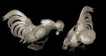 Par de Estatueta de galos de rinha (briga) em metal patnado de cinza, apresentando detalhes finos,  medindo 15cm x 24cm x 14cm e 16cm x 23cm x 12cm.