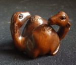 Espetacular netsuke de coleção  esculpido em madeira  nobre representando para de camelo, com assinatura,  comprimento 4 cm.