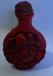 Diferente Snuff Bottle em masss da cor vinho com arte em relevo, em um dos lados a figura do rei macaco e do outro lado a figura de Buda com crianças. Alt.  8 cm - com 75g