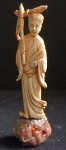 Escultura cor marfim chinês representando figura feminina oriental. Aplicações em ouro amarelo e rubis. Base em pedra preciosa bruta. Altura do marfim 10,5 cm. Altura total 13 cm.