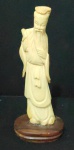 Escultura cor marfim chinês representando "Dignatário", apoiada sobre base em madeira. Med.: 15 cm. No estado