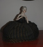 COLECIONISMO - BONECA EM PORCELANA AO GOSTO LLANDRO, PROVAVELMENTE EUROPA, VESTIDO DE FILÓ PRETO COM LISTAS DOURADAS. FALTA UMA DAS MÃOS. MED. 15CM ALT X 18 CM