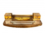 DIVERSOS, um (1) tinteiro confeccionado em madeira com decoração em marchetaria representando paisagem, possui cavidades e recorte na borda, 2 recipientes para tinta em vidro translucido, apresenta desgastes no verniz da tampa, medindo 8x23x21,5cm.