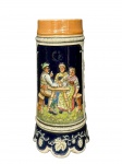 FAIANÇA, um (1) tankard confeccionado em faiança sueca com decoração de cachos de uva, folhas de parreira e elementos florais em relevo, cena típica de confraternização camponesa: três personagens trajados à moda tradicional, sentados à mesa em momento de celebração, em meio campestre em rica policromia, apresentando sinais de craquele, caixa musical no fundo, funcionando, porém, sem garantias futuras, medindo 23cm de altura.