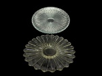 CRISTAL e VIDRO, lote com dois (2) pratos para bolo, sendo: A) 1 confeccionado em cristal translucido com lapidação de caneluras e perolados, borda dentada, medindo 30cm, apresentando bicados na borda e B) 1 confeccionado em vidro translucido moldado por repuxados e bordas em ondulações, medindo 26cm.