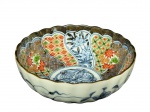 PORCELANA ORIENTAL, um (1) bowl em porcelana na tonalidade branca, apresentando borda ondulada com acabamento dourado, decoração policromada no interior em painéis segmentados com motivos florais, geométricos e arabescos de inspiração oriental, centro ornado por medalhão circular floral em azul sob o vidrado; parte externa decorada em azul sob fundo claro, com motivos florais e elementos orgânicos, fundo marcado, medindo 5x14cm.
