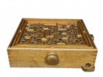 DIVERSOS, um (1) jogo de labirinto composto por caixa retangular em madeira natural, com tampa deslizante e tabuleiro interno com percurso em relevo, apresentando trilhas, obstáculos e perfurações circulares, conforme modelo tradicional de jogo de destreza, manípulos laterais em madeira, destinados ao controle do tabuleiro, permitindo a movimentação da esfera pelo percurso, medindo 10x36x32cm.